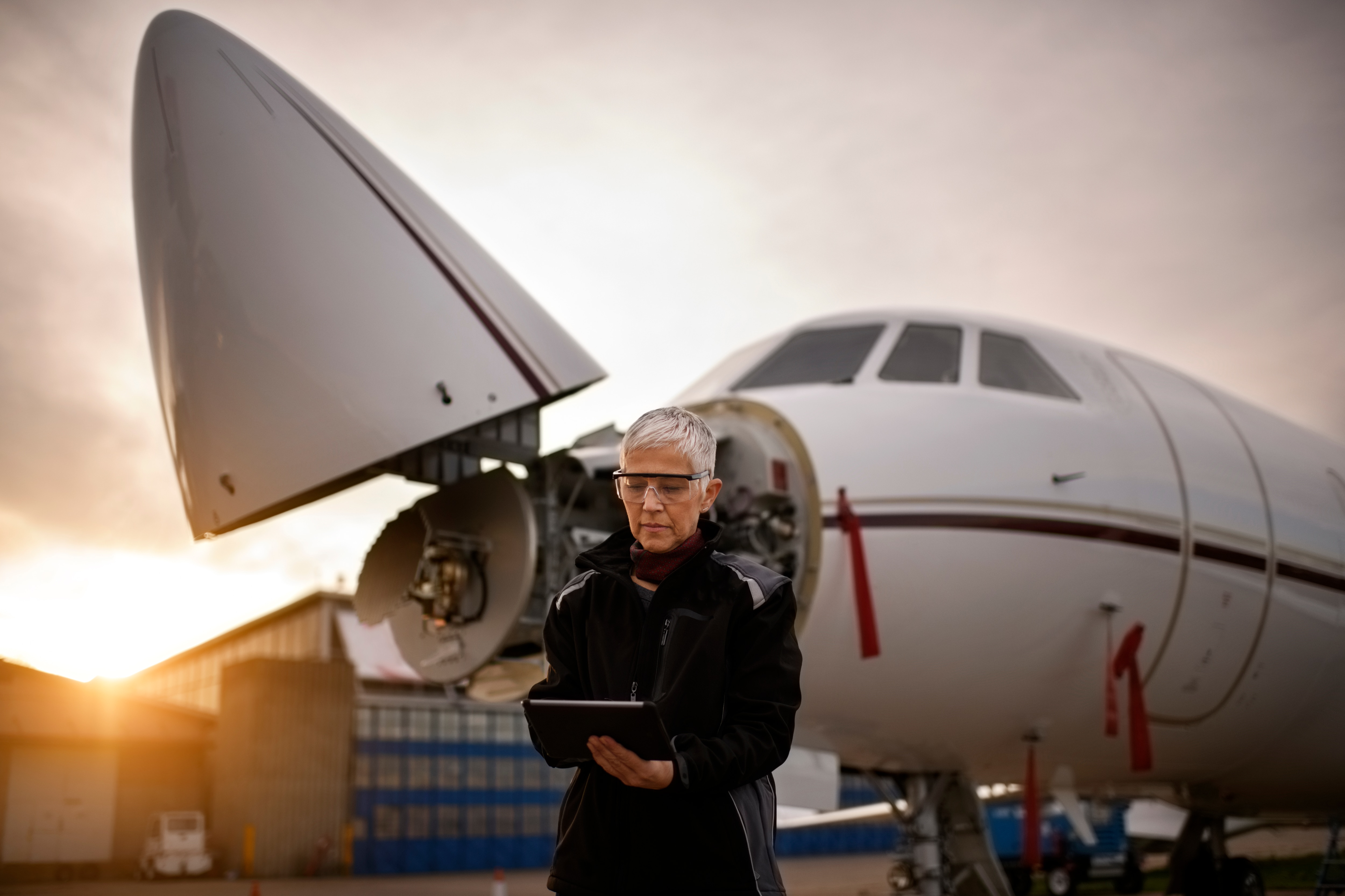 woman working in aerospace holding tablet wearing safety glasses