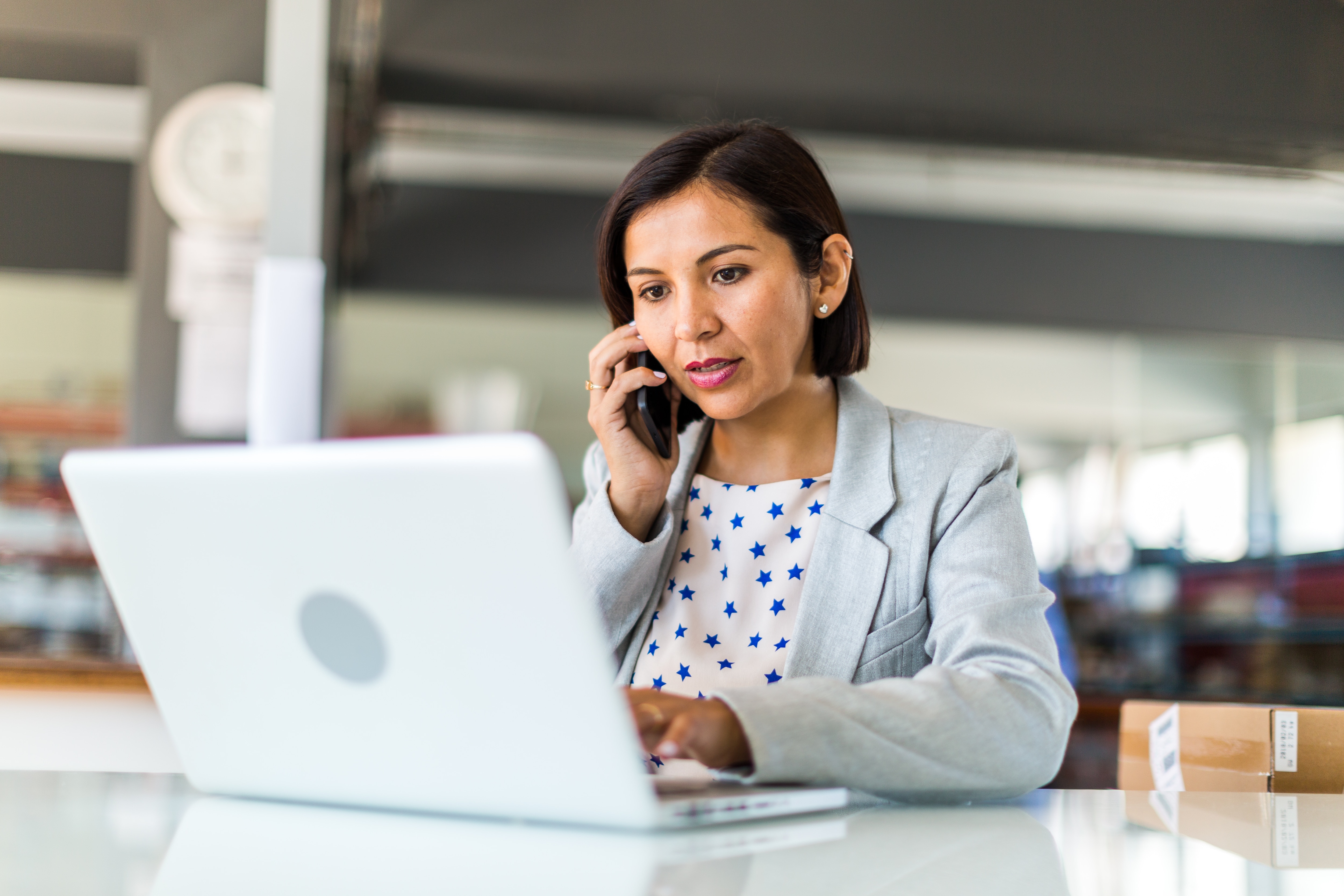 Lady on phone while typing on a computer in the office