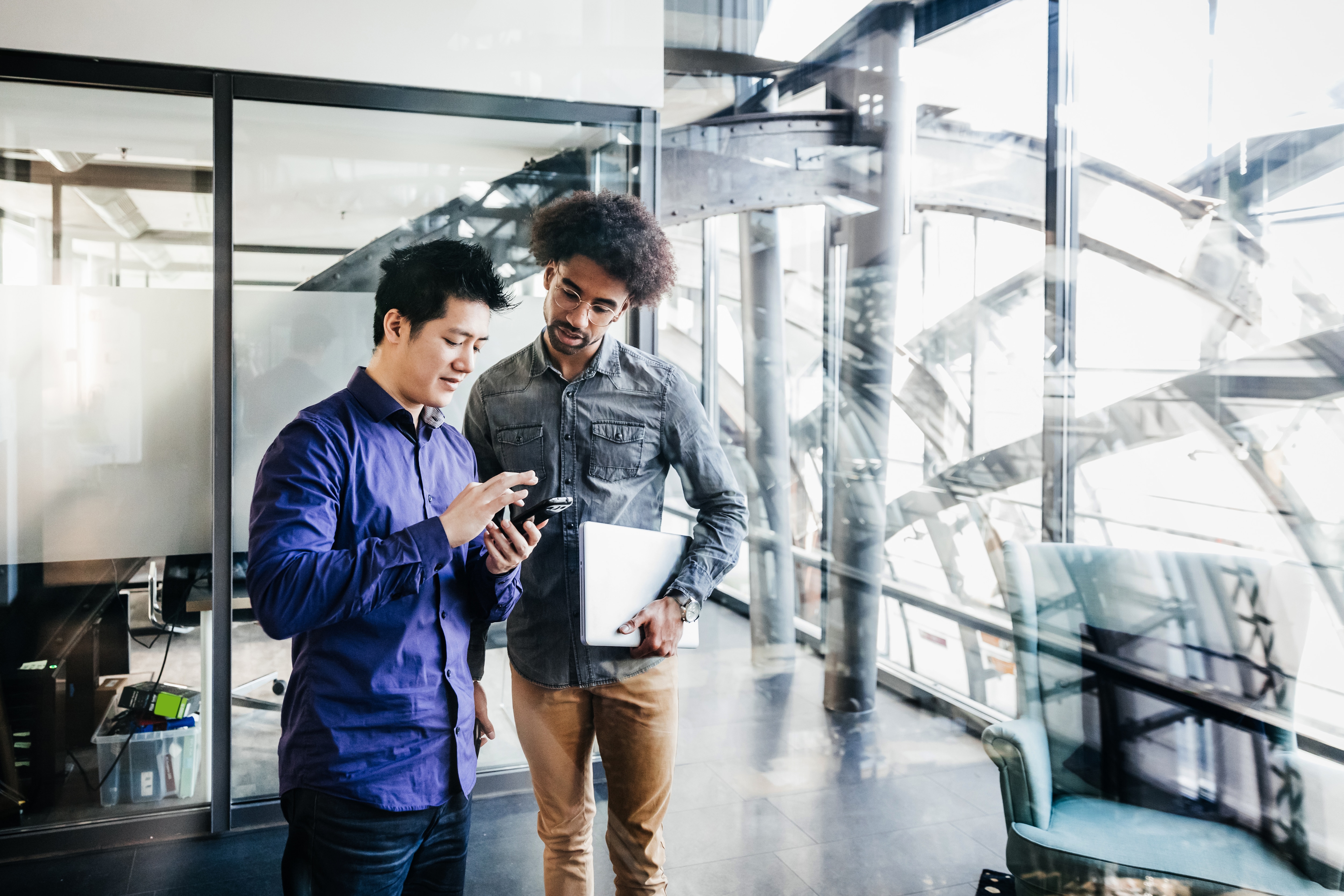 Two men in an office looking at a phone