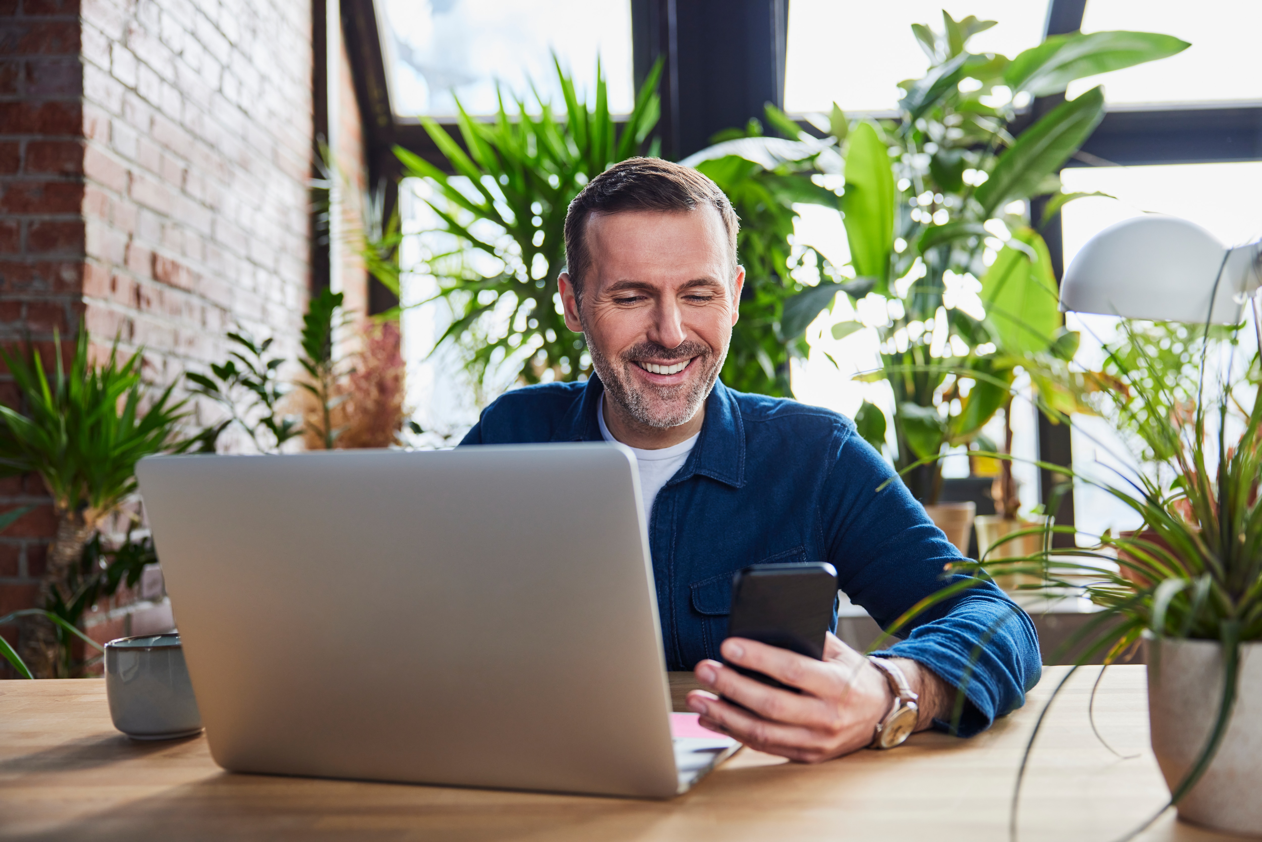 a man sitting by a table using his digital devices