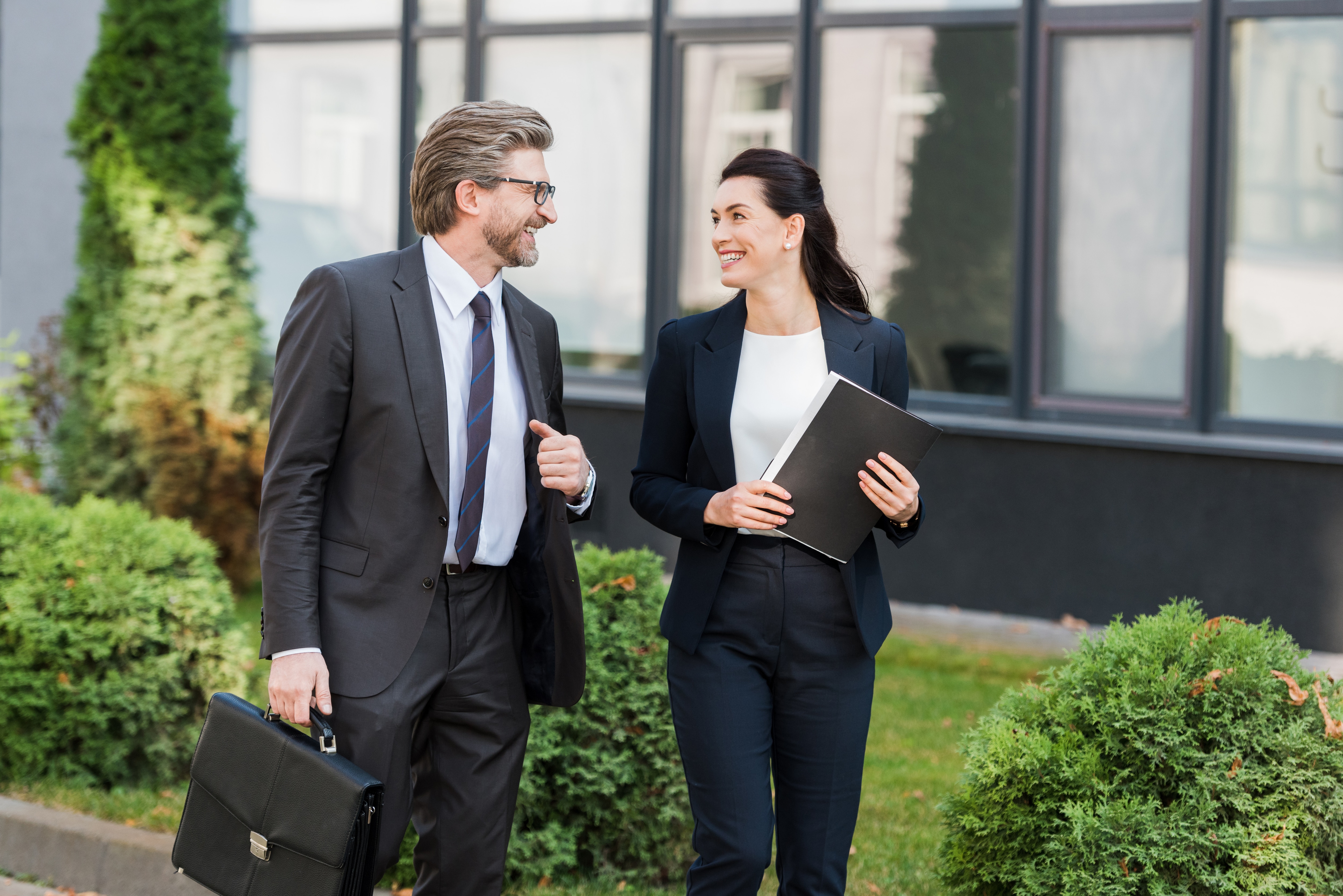 A man and a woman in black suits chatting about Concur Cloud for Public Sector