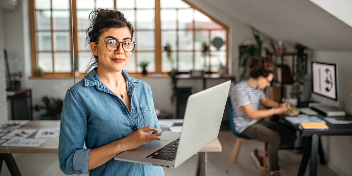 woman with glasses holding computer