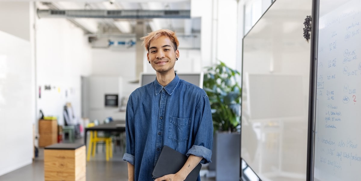 young asian tech worker with blonde hair holding computer